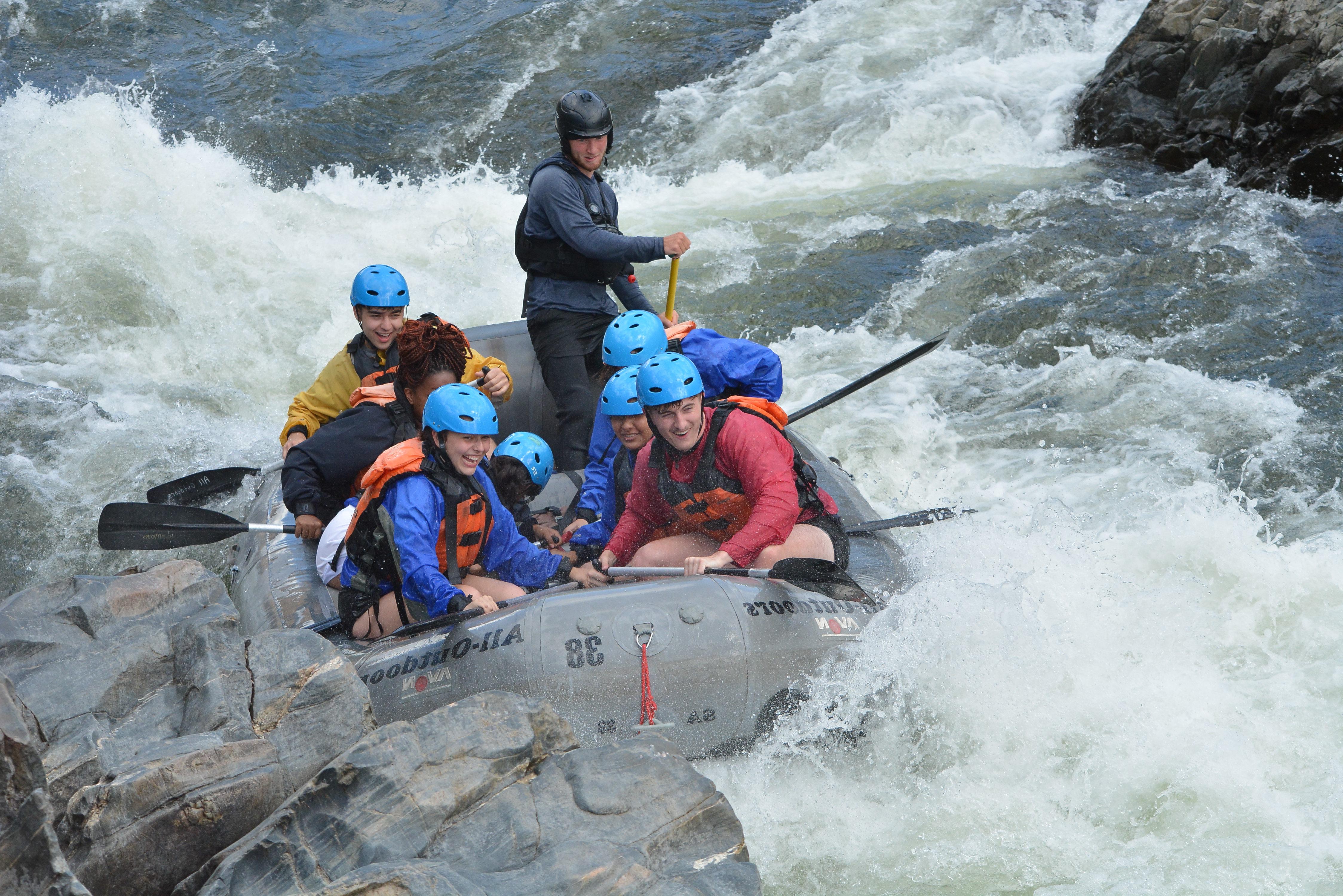 Students in rafting boat going down a rapid