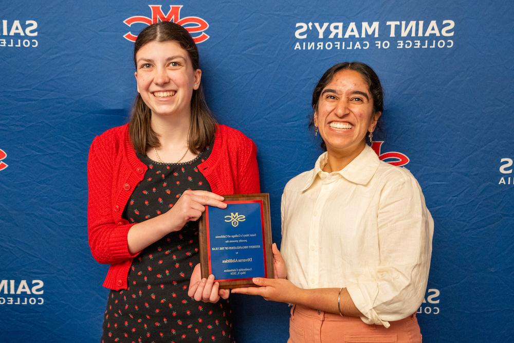 多元化学生领袖Sahiba Kuar Dogra和莫莉Floberg举着2024年学生领袖奖的牌匾