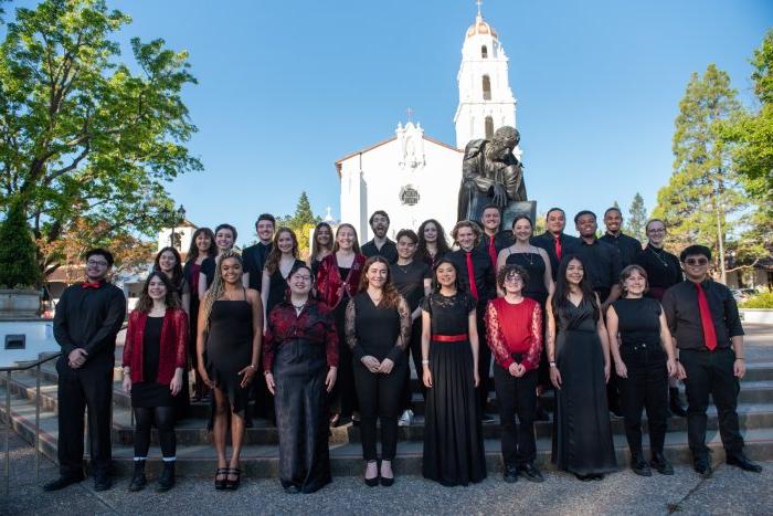 十大正规网赌平台唱诗班身穿红黑相间的服装，站在SMC教堂和施洗约翰·德·拉萨尔雕像前，头顶蓝天.